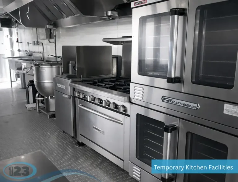 Mobile kitchen trailer interior with gas range, commercial oven, kettle cooker, prep area, and stainless steel ventilation system
