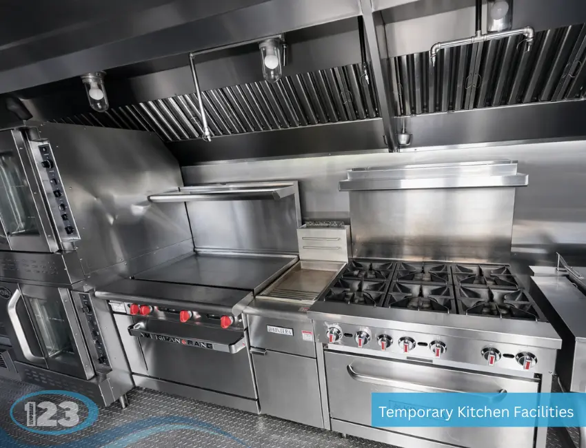 Commercial cooking line inside mobile kitchen trailer with gas range, flat top griddle, oven, and ventilation hood system